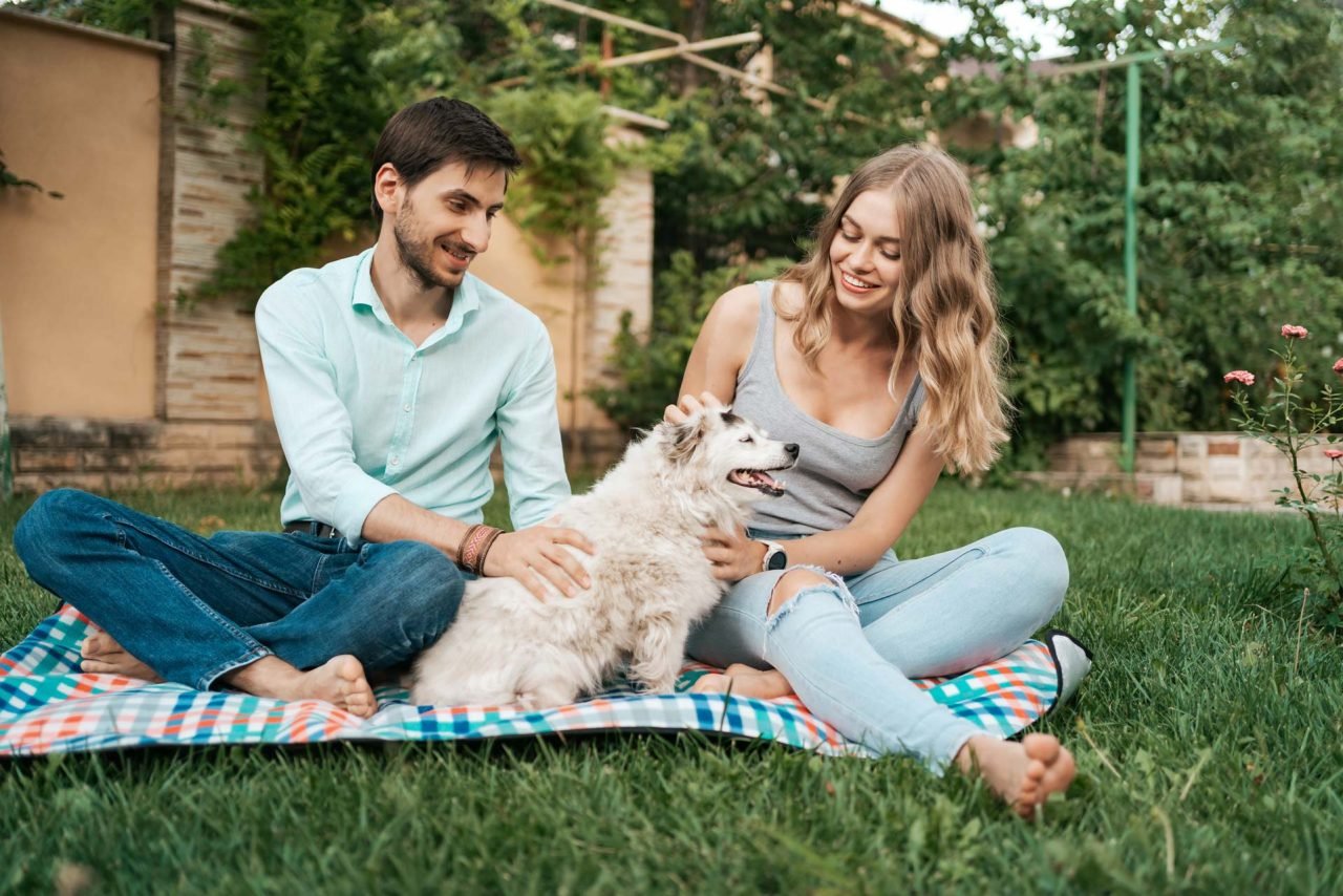 beautiful-couple-with-a-dog-on-the-grass